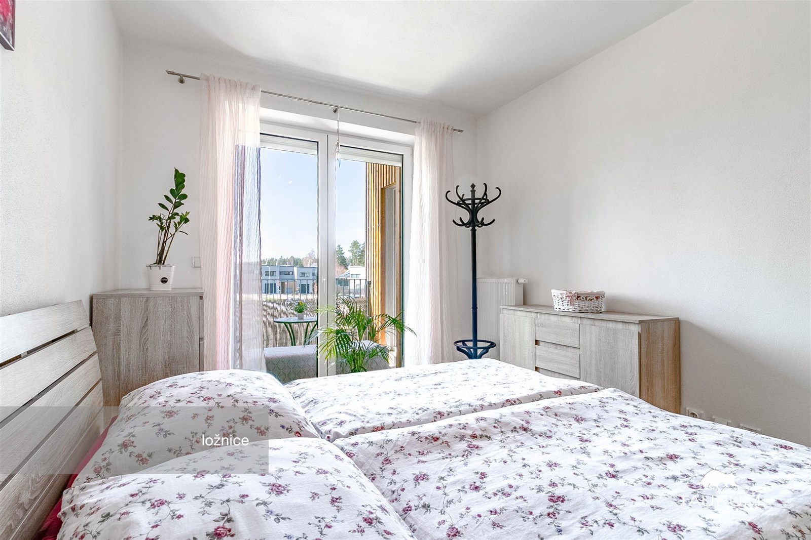 Prostorná ložnice s velkými okny a parketovou podlahou, moderní styl a výhled na terasu, světlá atmosféra a kvalitní nábytek.