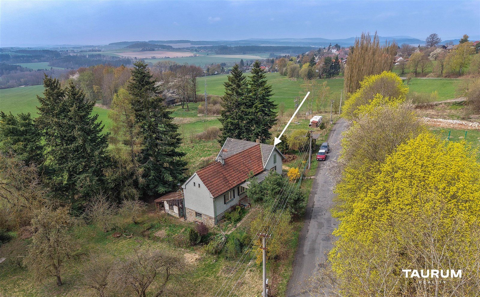 Rodinný dům na venkově, obklopený zelení a stromy,