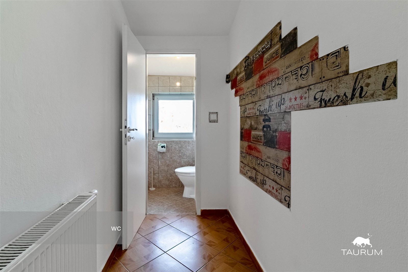 Úzká chodba s dlažbou a radiátorem, vedoucí do kou