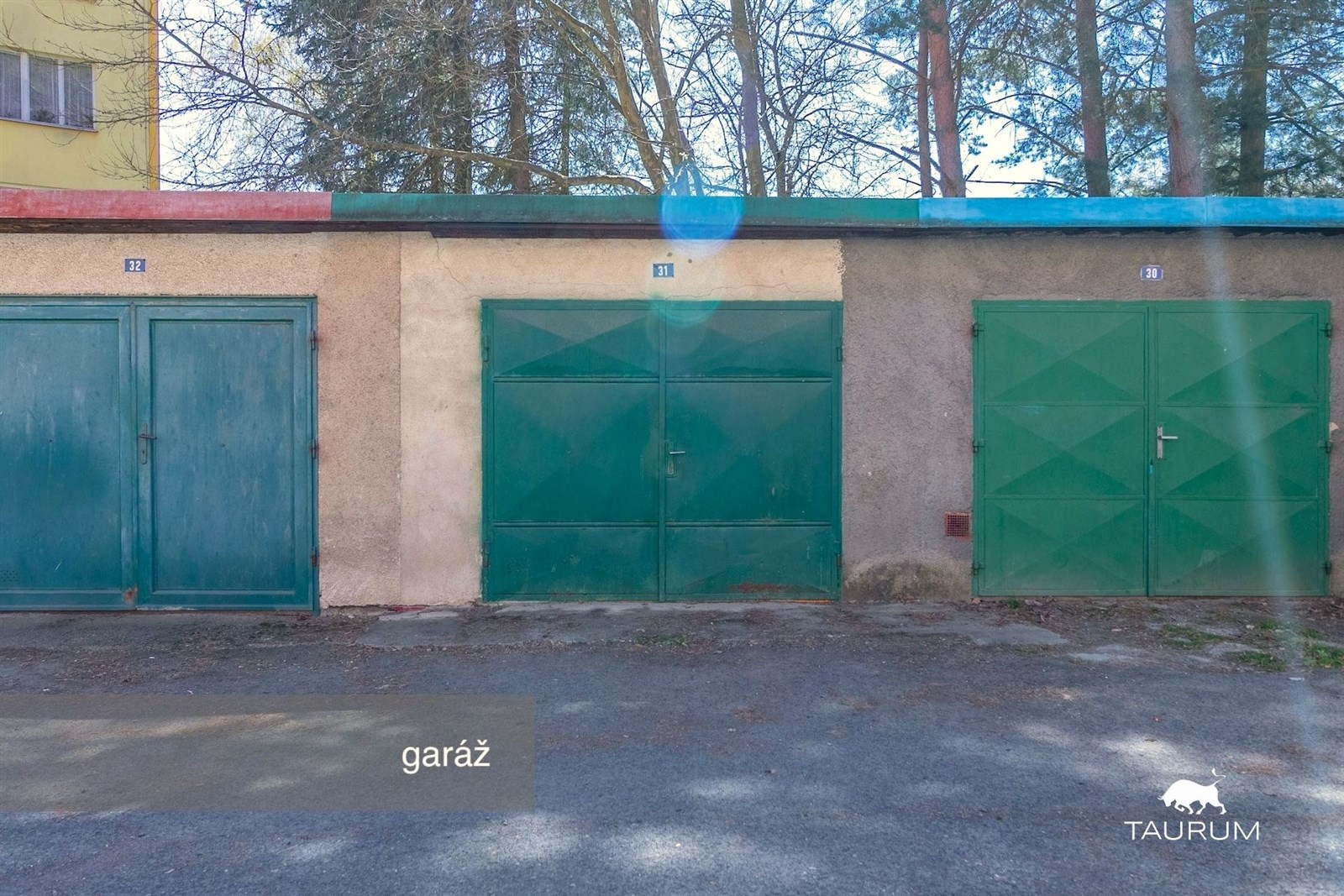 Uzavřená garáž s kovovými vraty, umístěná v řadové zástavbě.