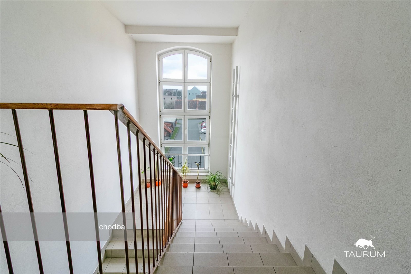 Prostorné schodiště s dlažbou, velkým obloukovým o