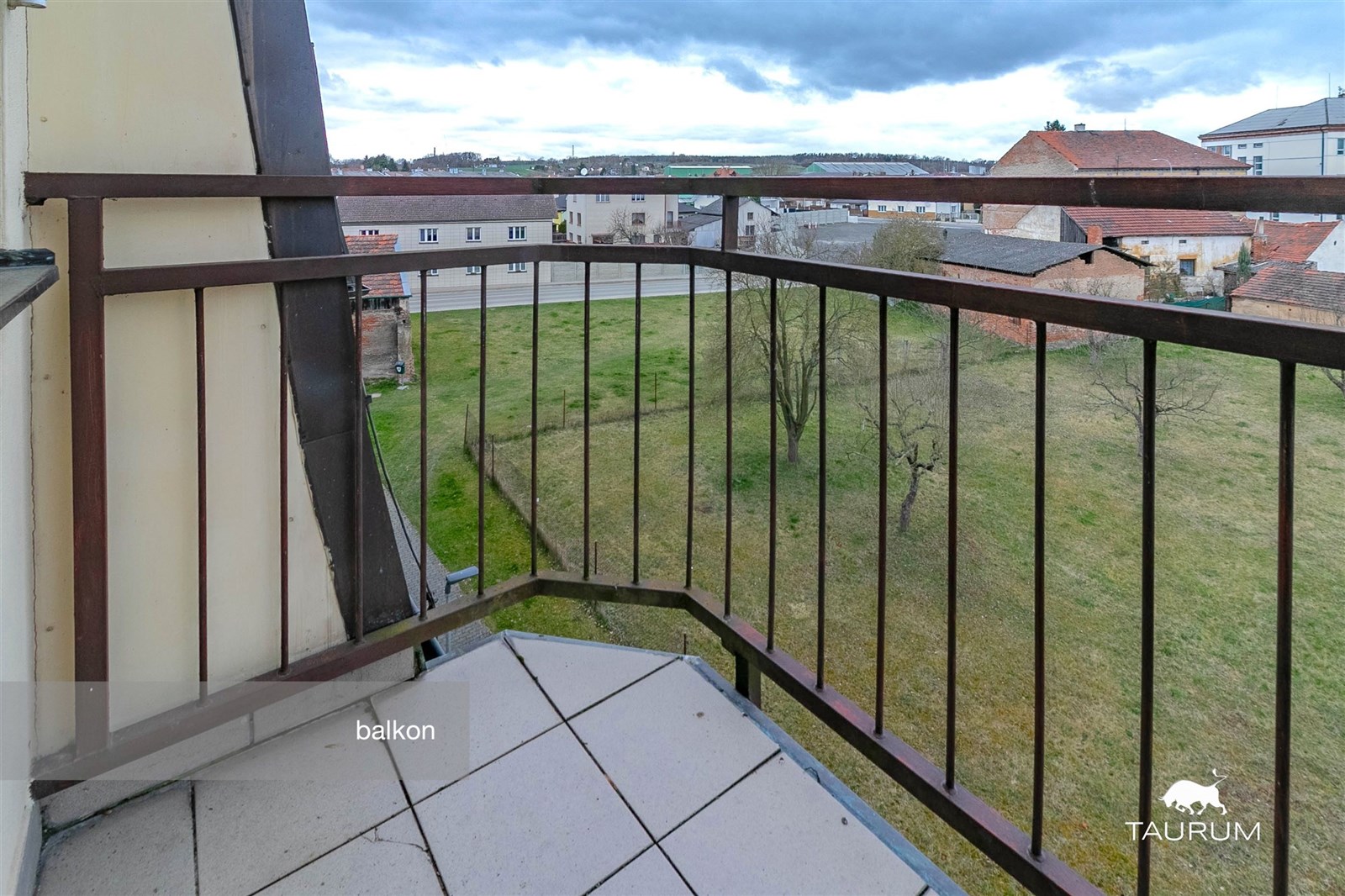 Balkon s dlažbou a výhledem na zahradu, železné zá