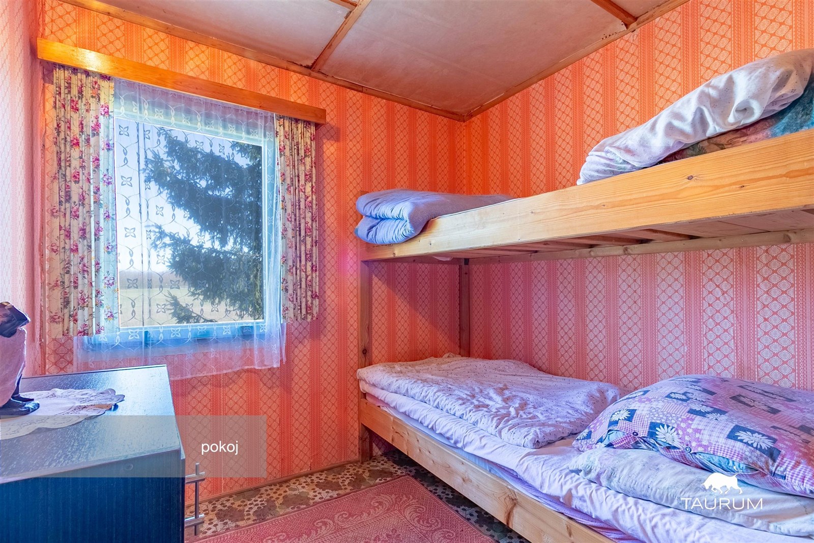 Pokoj s palandou, retro tapety a koberec, dřevěný nábytek, přírodní osvětlení oknem, útulný styl vhodný pro rekonstrukci nebo modernizaci.