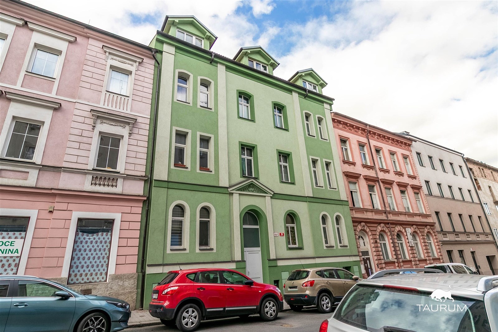 Historický činžovní dům se zelenou fasádou, situov