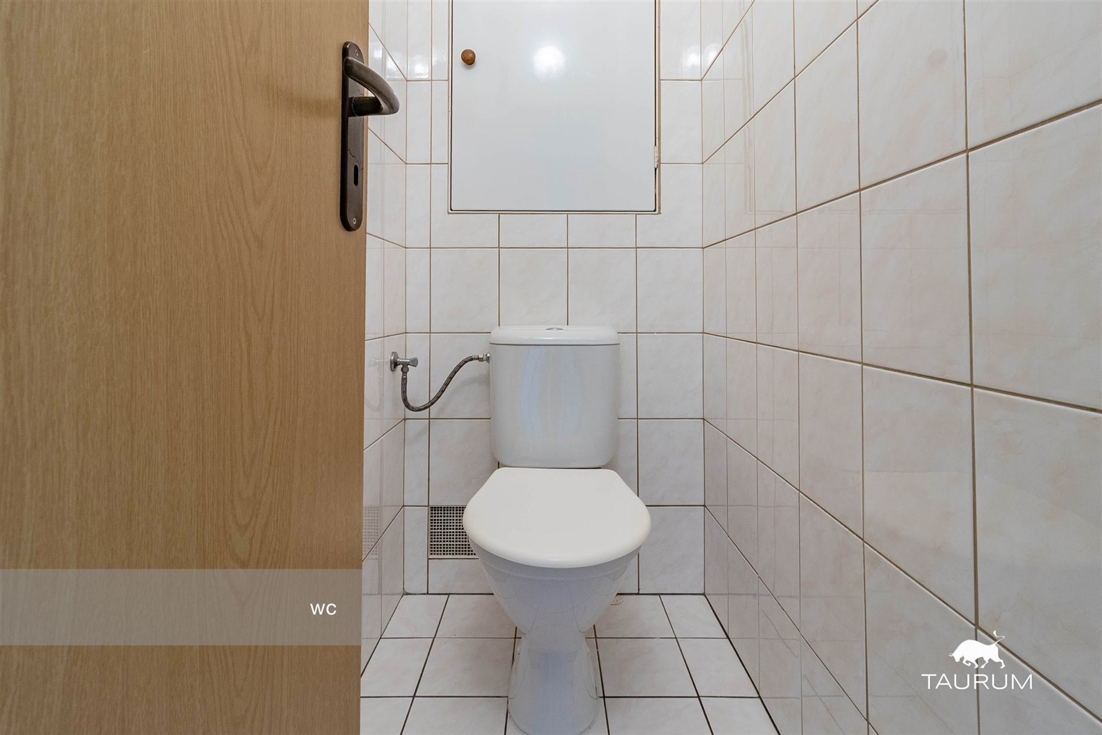 Toaleta s bílou dlažbou, světlé obklady a dřevěné 