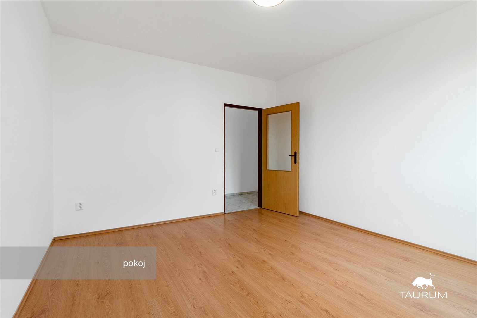 Prázdný pokoj s parketovou podlahou, bílými stěnam