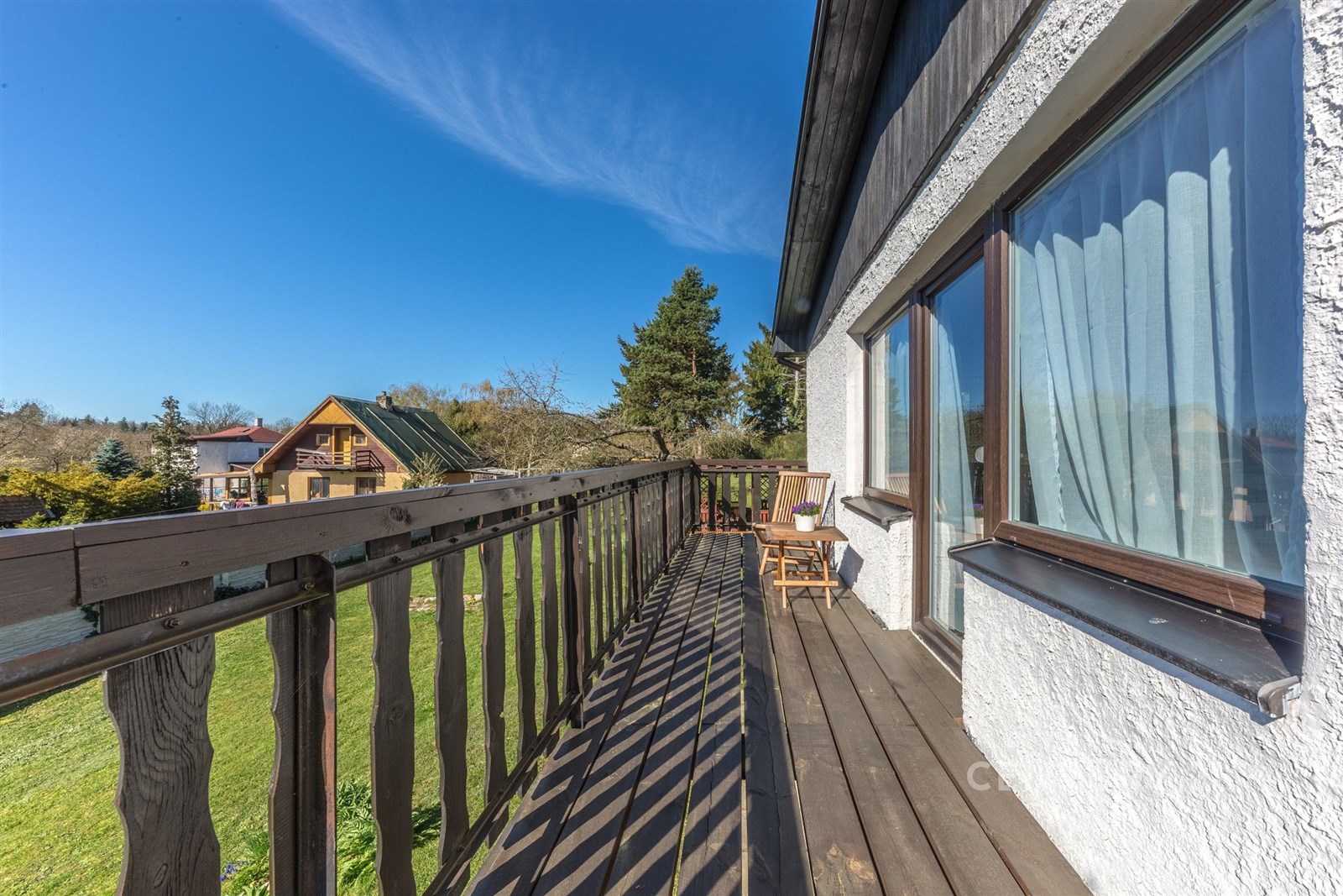 Dřevěný balkon s výhledem do zahrady, dřevěná podlaha, velká okna, klidná lokalita, vhodné pro milovníky přírody.