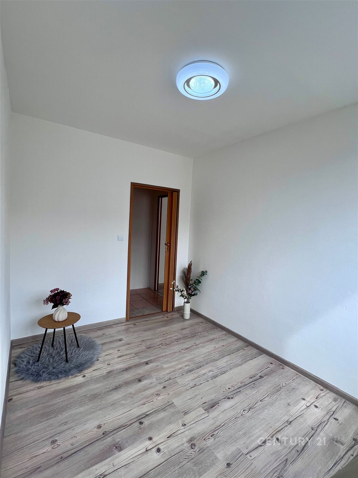 Prázdná místnost s dřevěnou podlahou a bílými stěn