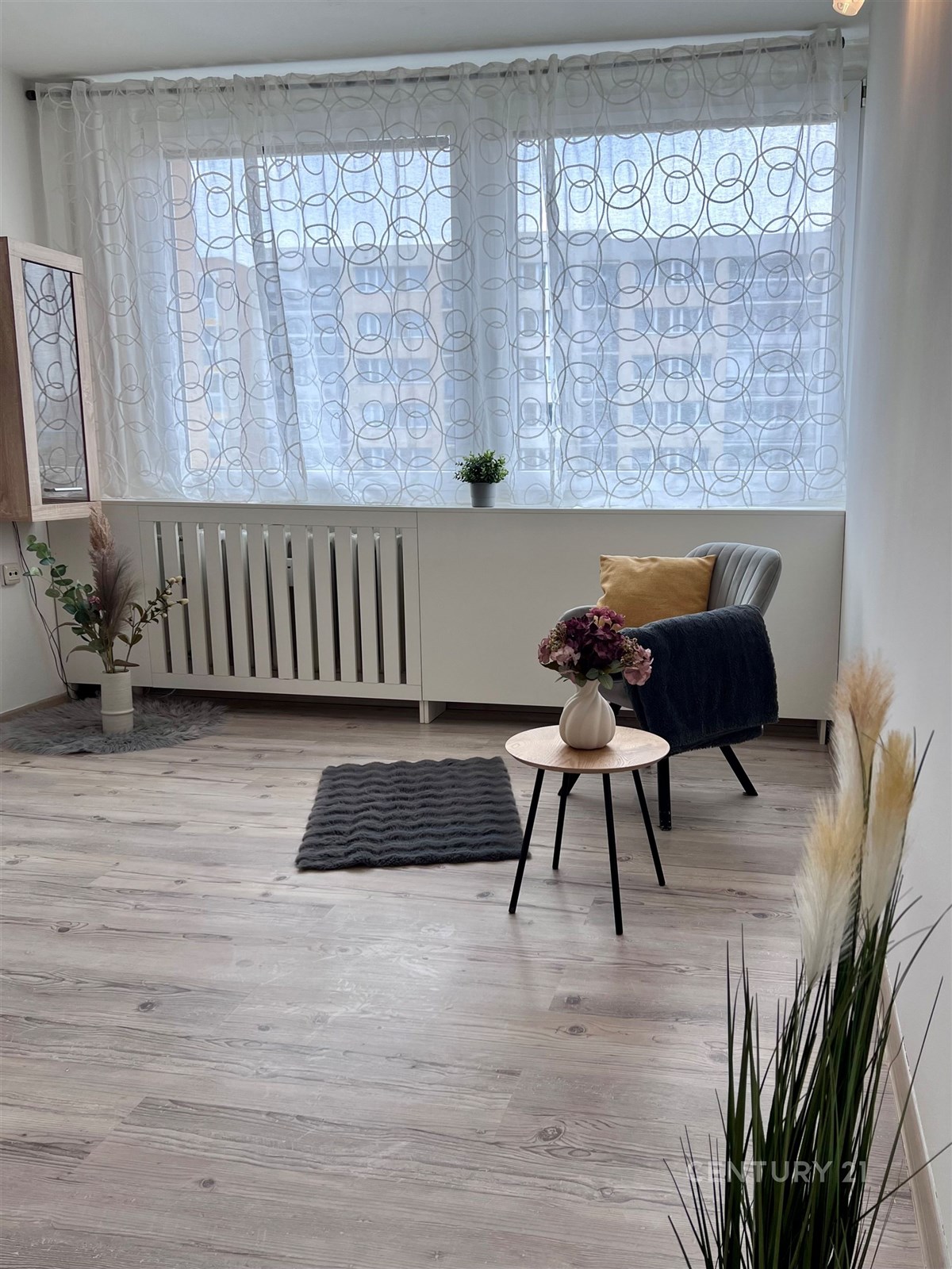 Světlý obývací pokoj s parketovou podlahou a velký