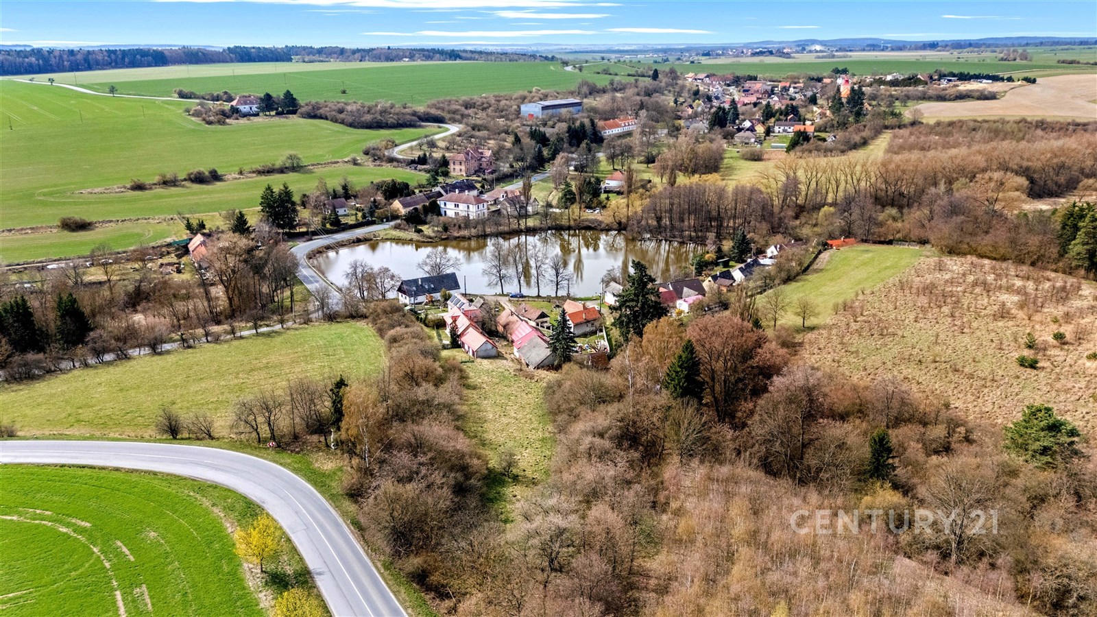 Jezero obklopené zelení a vesnickými domy, venkovs