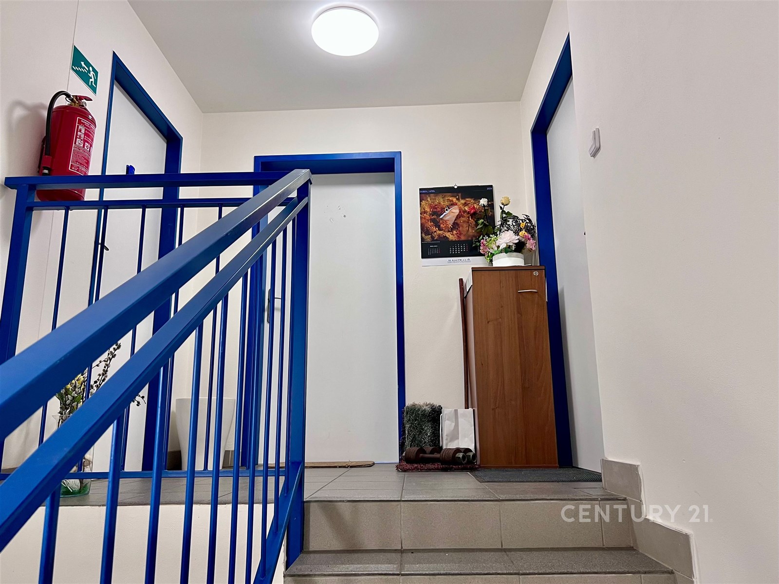 Chodba bytového domu s dlažbou, modrým zábradlím a