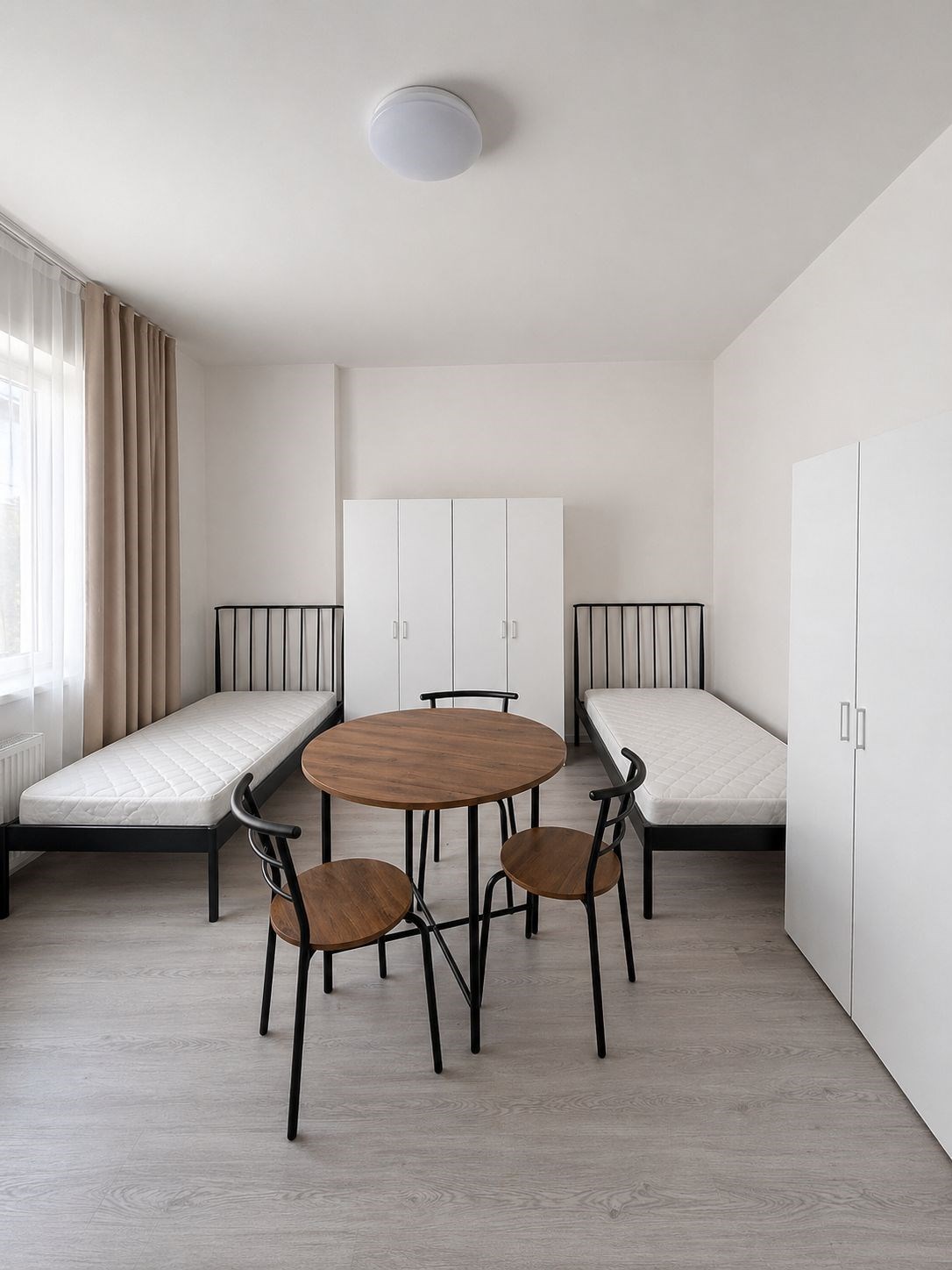 Minimalistická ložnice, světlá místnost, laminátová podlaha, dvě postele, moderní nábytek, vysoké stropy, praktické uspořádání nábytku.