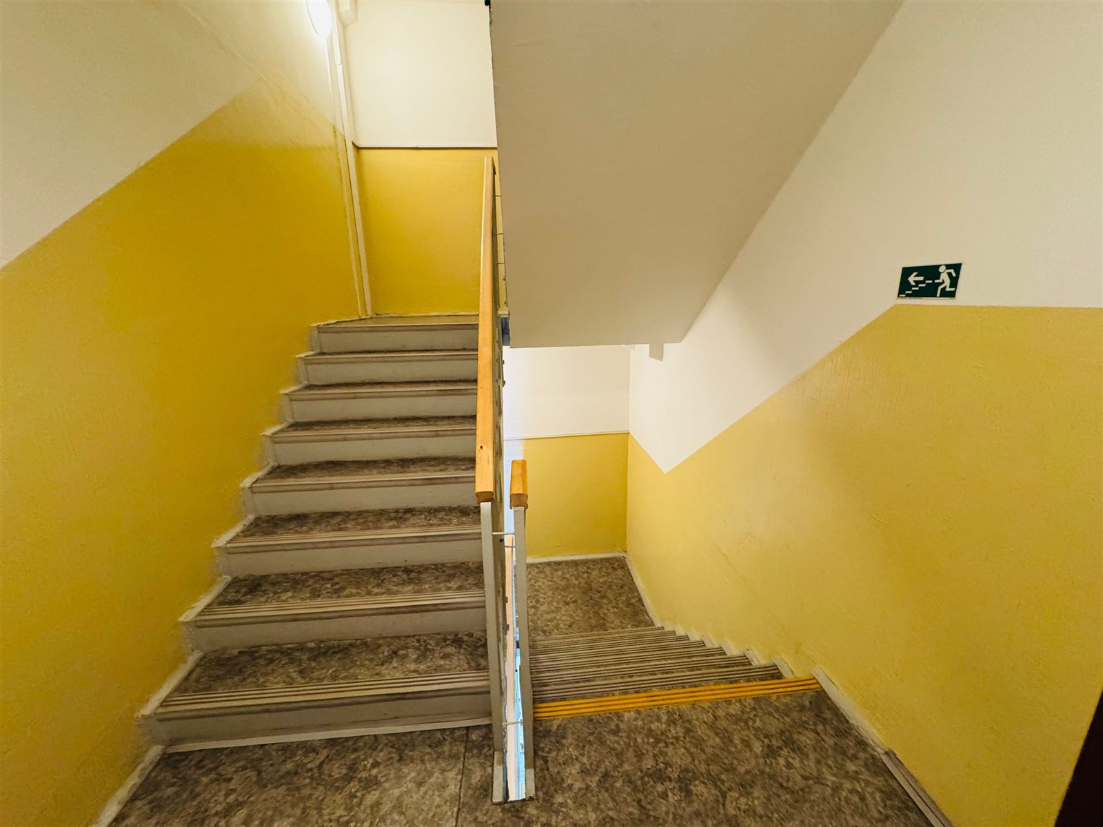 Průchodová chodba s betonovým schodištěm a kovovým