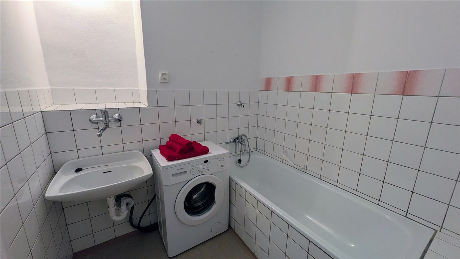 Koupelna s vanou, pračkou a umyvadlem, obložená bí