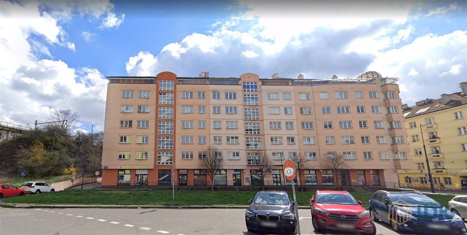 Vícepatrový bytový dům s růžovou fasádou a mnoha o