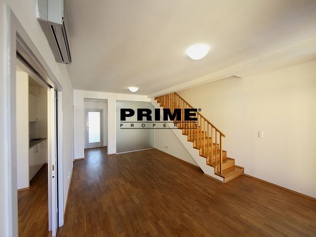 Prostorný obývací pokoj, parketová podlaha, dřevěné schodiště, světlý interiér, moderní klimatizace, otevřený prostor.