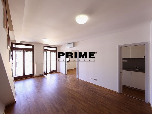 Světlý obývací pokoj s parketovou podlahou, velká okna, moderní styl, možnost připojení na klimatizaci.