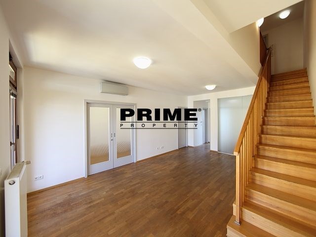 Prostorný obývací pokoj s parketovou podlahou a moderním osvětlením, schodiště s dřevěnými prvky, ideální pro rodinné bydlení