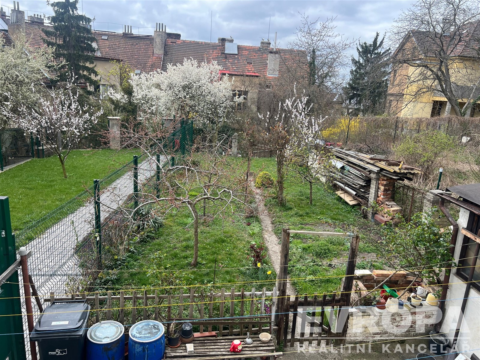 Zahrada s ovocnými stromy, dřevěným oplocením a tr