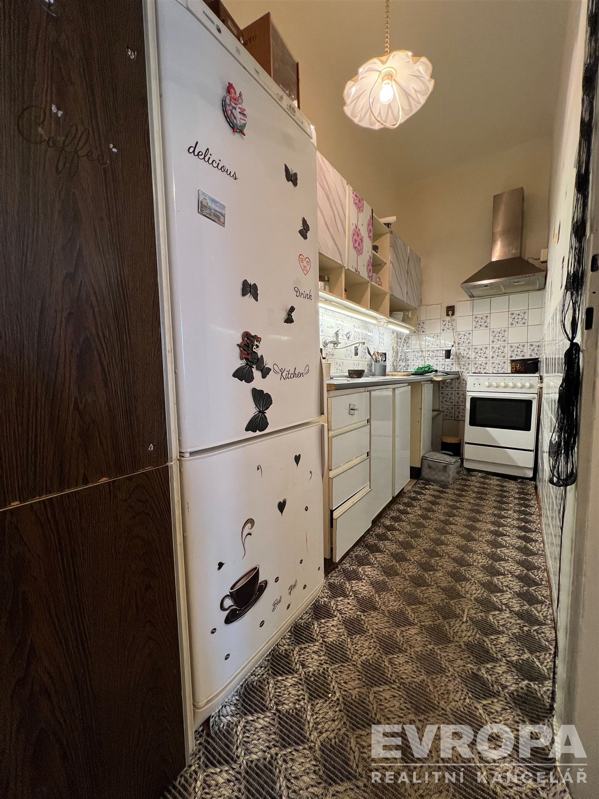 Úzká kuchyň s kachlovou podlahou a bílými spotřebi