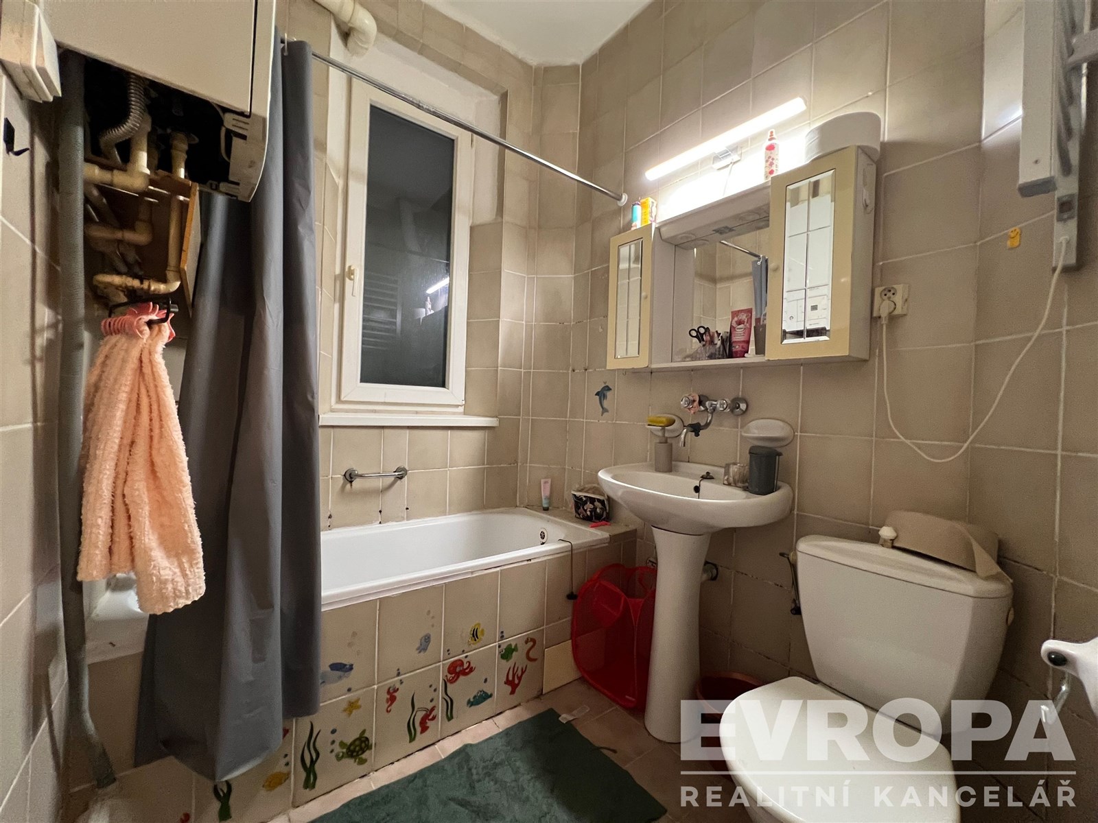 Koupelna s dlažbou, vanou a závěsnou skříňkou, obs