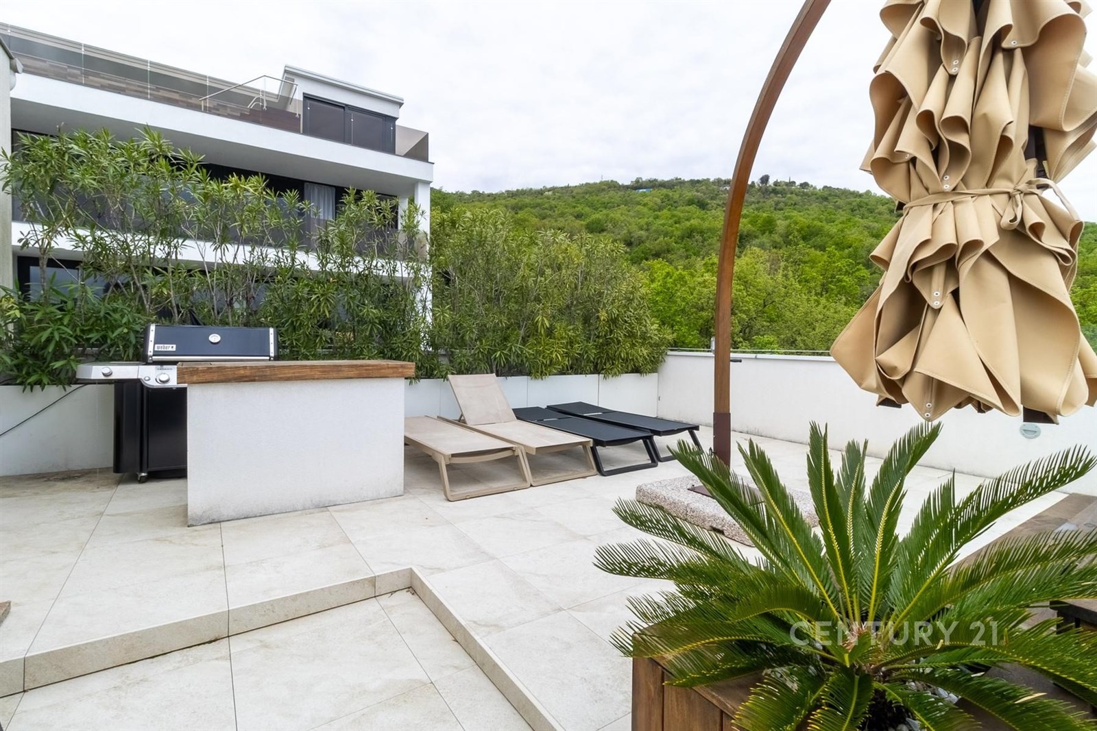 Střešní terasa s dlažbou, moderní gril a lehátka, výhled na zeleň, ideální pro relaxaci a venkovní zábavu, dobře udržovaný prostor