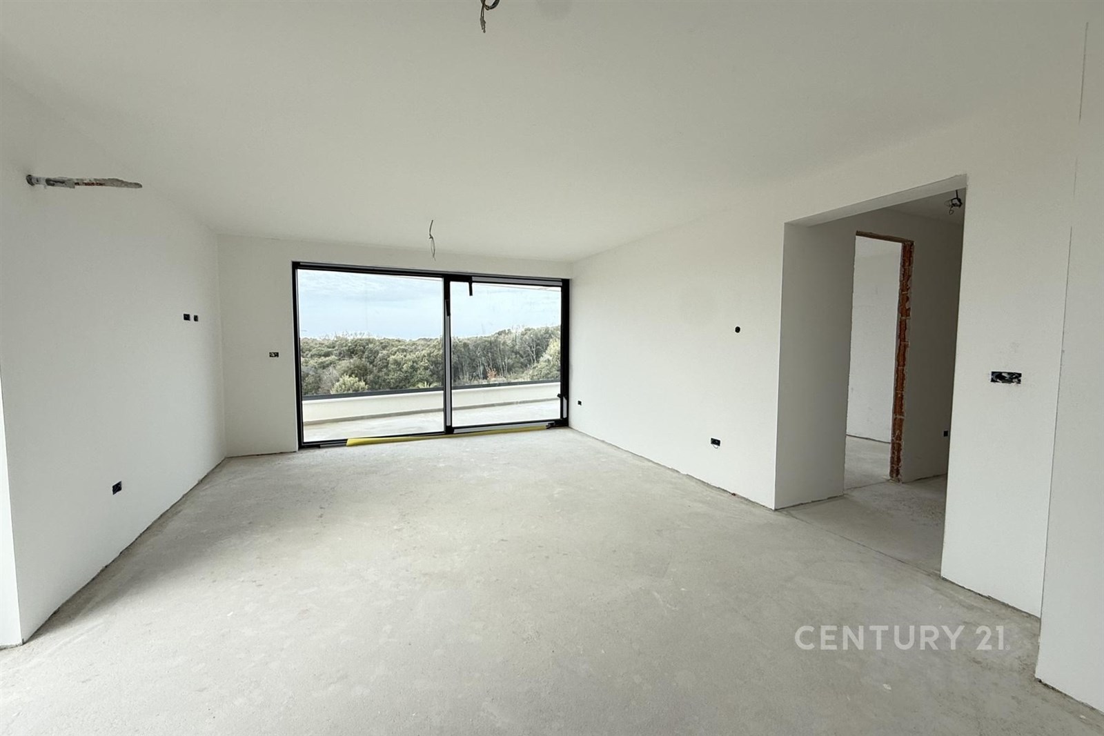 Světlý obývací pokoj s velkými okny, moderní betonová podlaha, výhled do zeleně, vhodný pro otevřený design interiéru