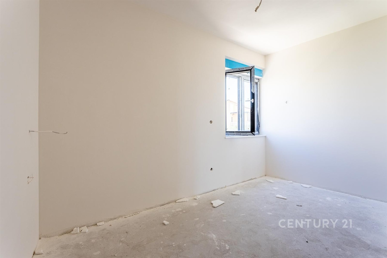 Prázdný pokoj s bílými stěnami, betonovou podlahou