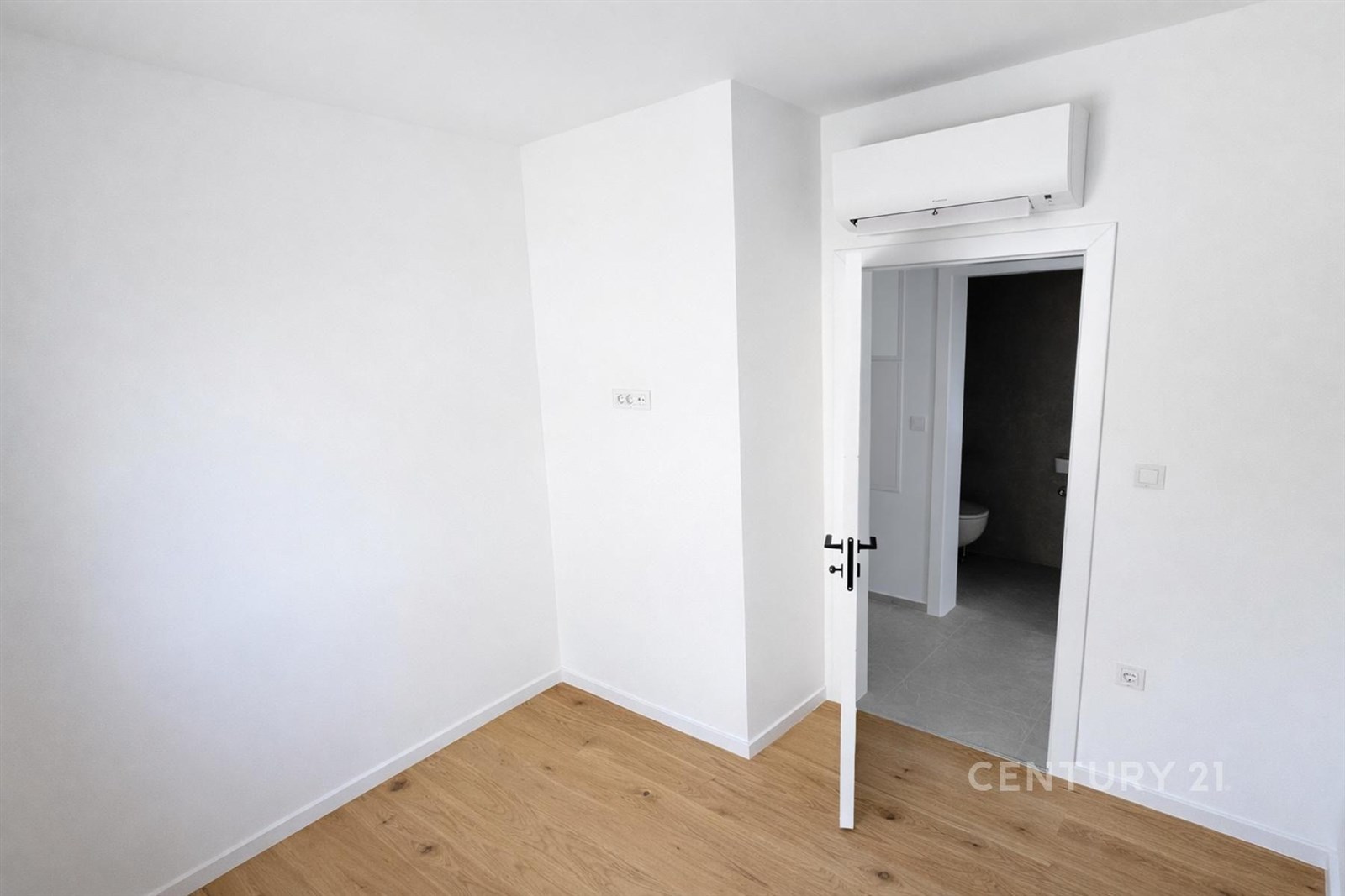 Světlý pokoj s dřevěnou podlahou, bílými stěnami a