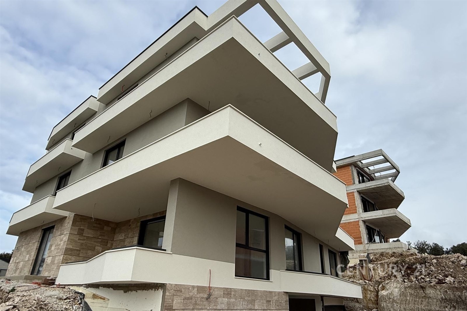 Moderní bytový dům s terasami, elegantní fasáda, velká okna a čisté linie, což zajišťuje světlé a prostorné interiéry.