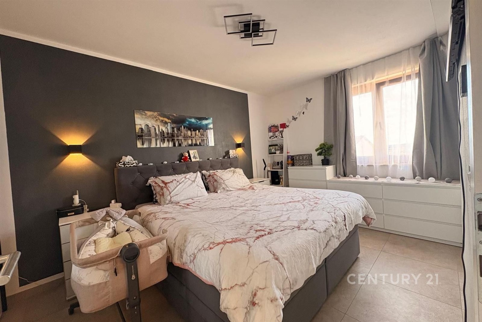 Prostorná ložnice s moderním stylem, dlažba na podlaze, velká okna poskytují dostatek světla, vestavěné skříně nabízejí úložný prostor.