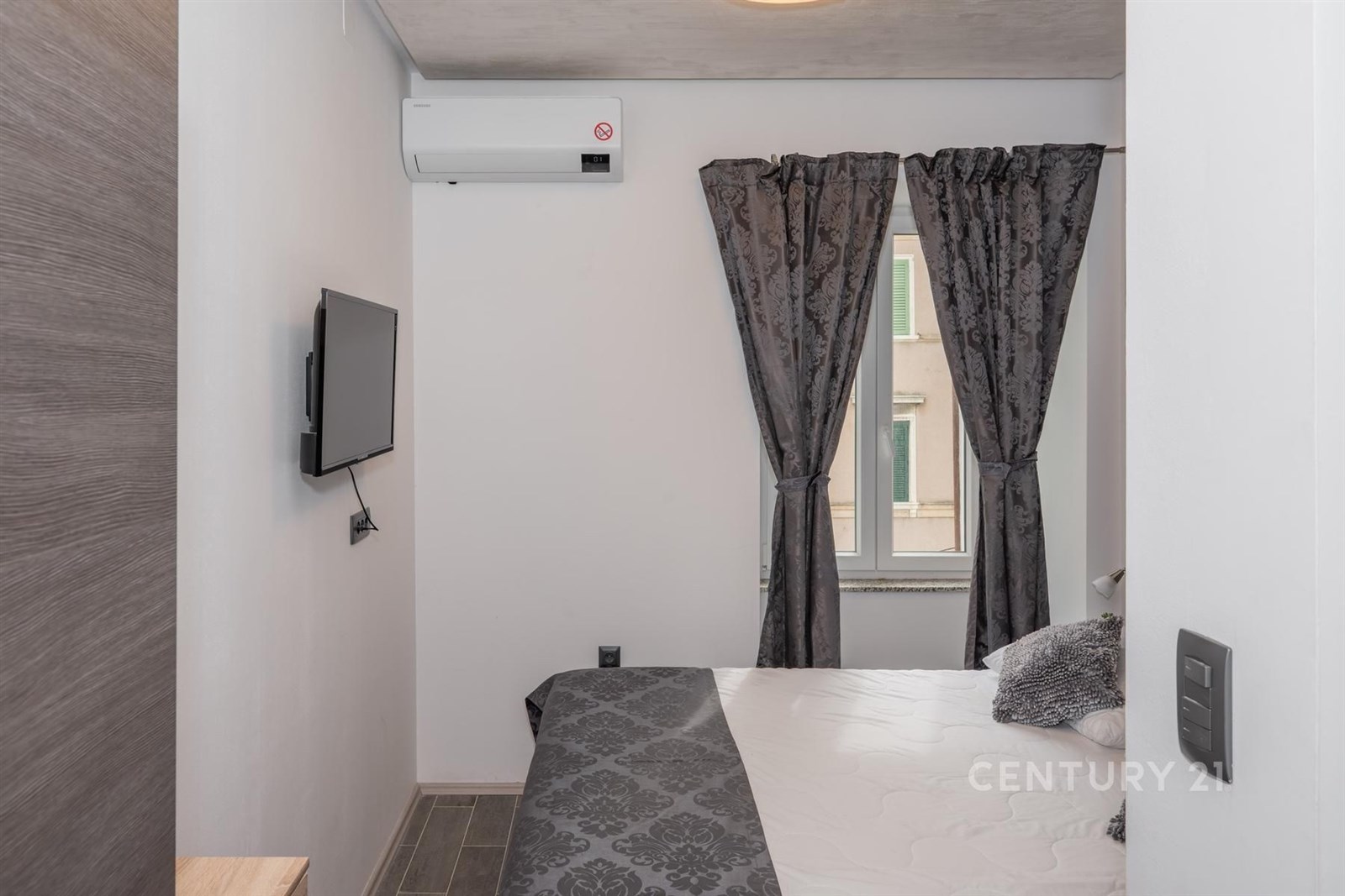 Malá ložnice s moderní klimatizací, tmavou textilní dekorací a laminátovou podlahou nabízí útulnou atmosféru a stylový design.