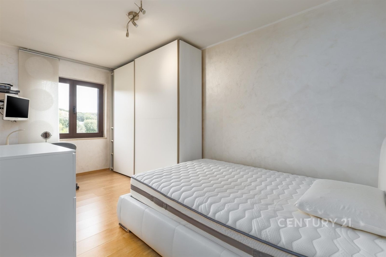 Světlá ložnice s parketovou podlahou, vestavěné skříně a moderní nábytek nabízí pohodlné bydlení.