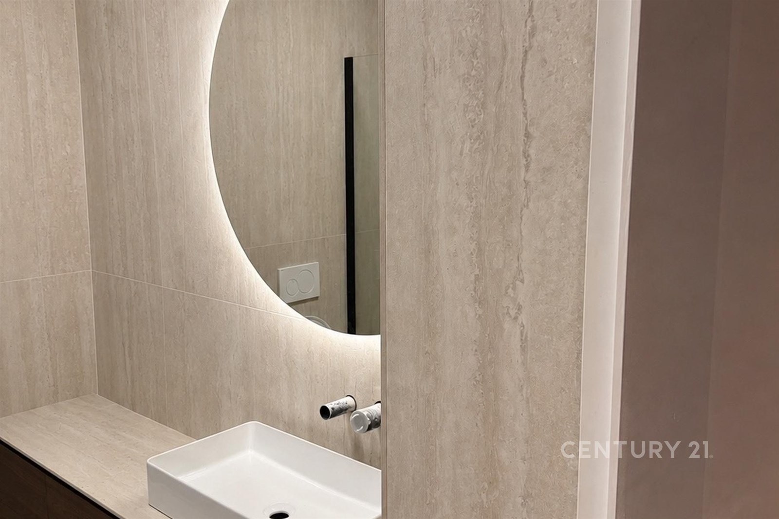 Světlý obývací pokoj s parketovou podlahou, velkými okny a moderním nábytkem. Stěny zdobí přírodní kámen, vytvářející elegantní atmosféru.