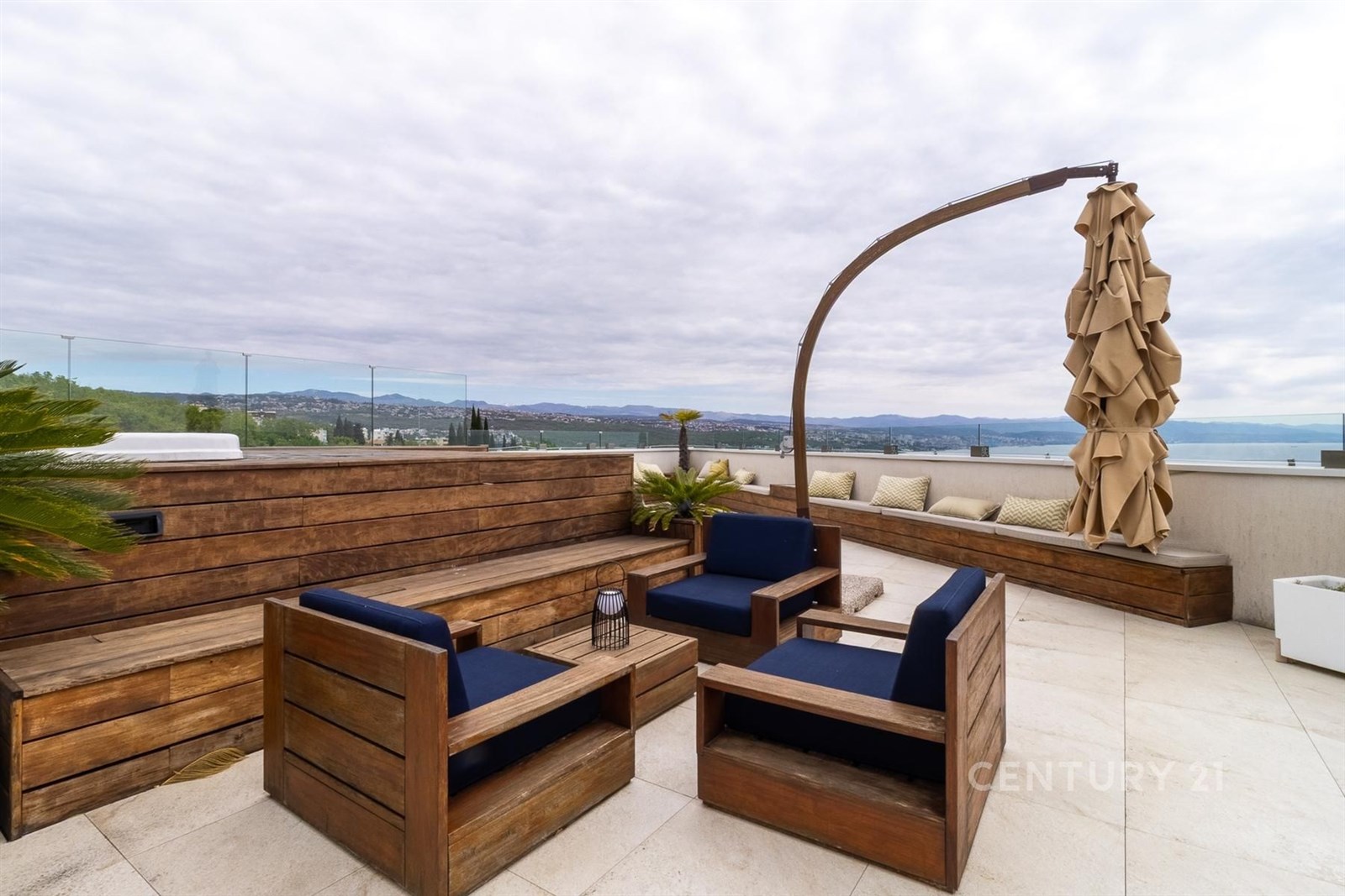 Prostorná terasa s dřevěným nábytkem nabízí panoramatický výhled, moderní dlažbu a minimalistický styl, ideální pro relaxaci.