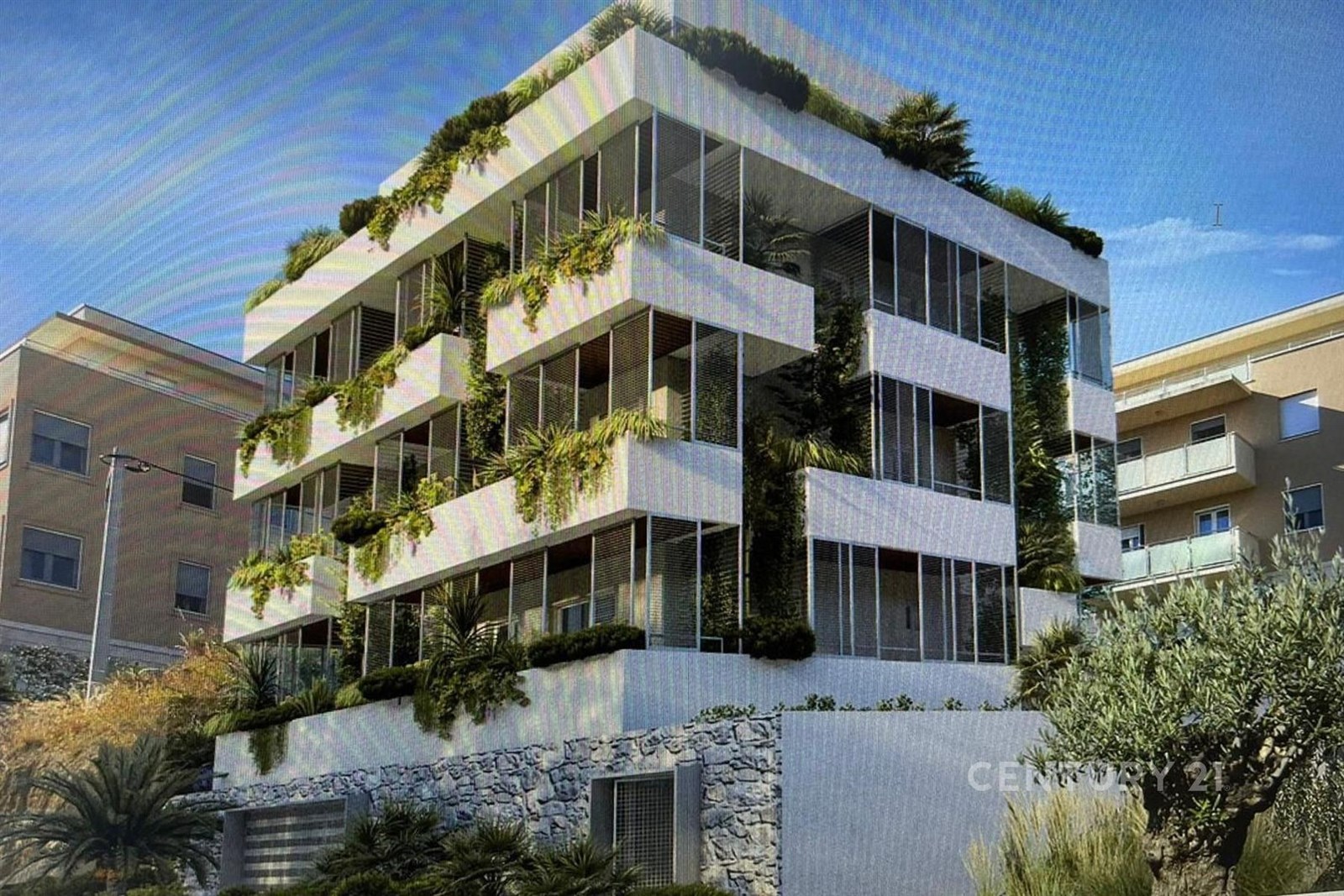 Moderní budova s velkými okny a zelení na fasádě, obložená přírodním kamenem, nabízí unikátní design ve městském prostředí.