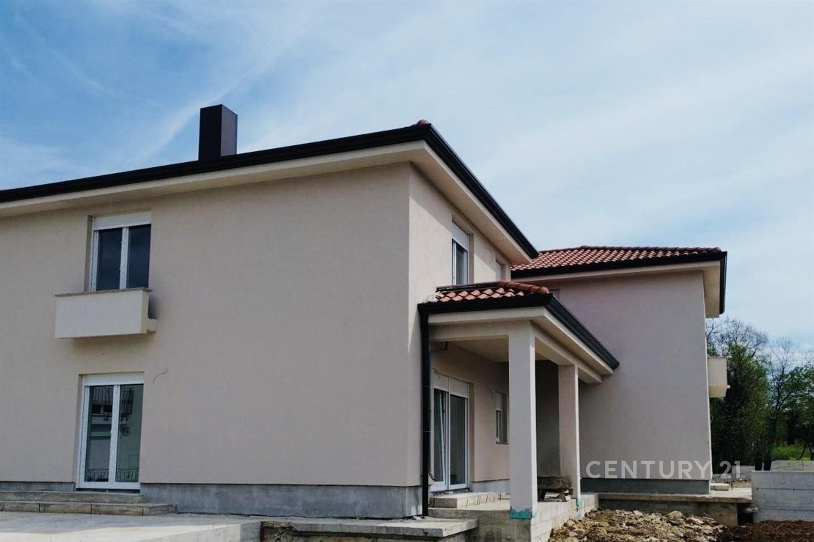 Moderní rodinný dům s červenou taškovou střechou, světlou fasádou a velkými okny na nově upraveném pozemku, připravený k nastěhování