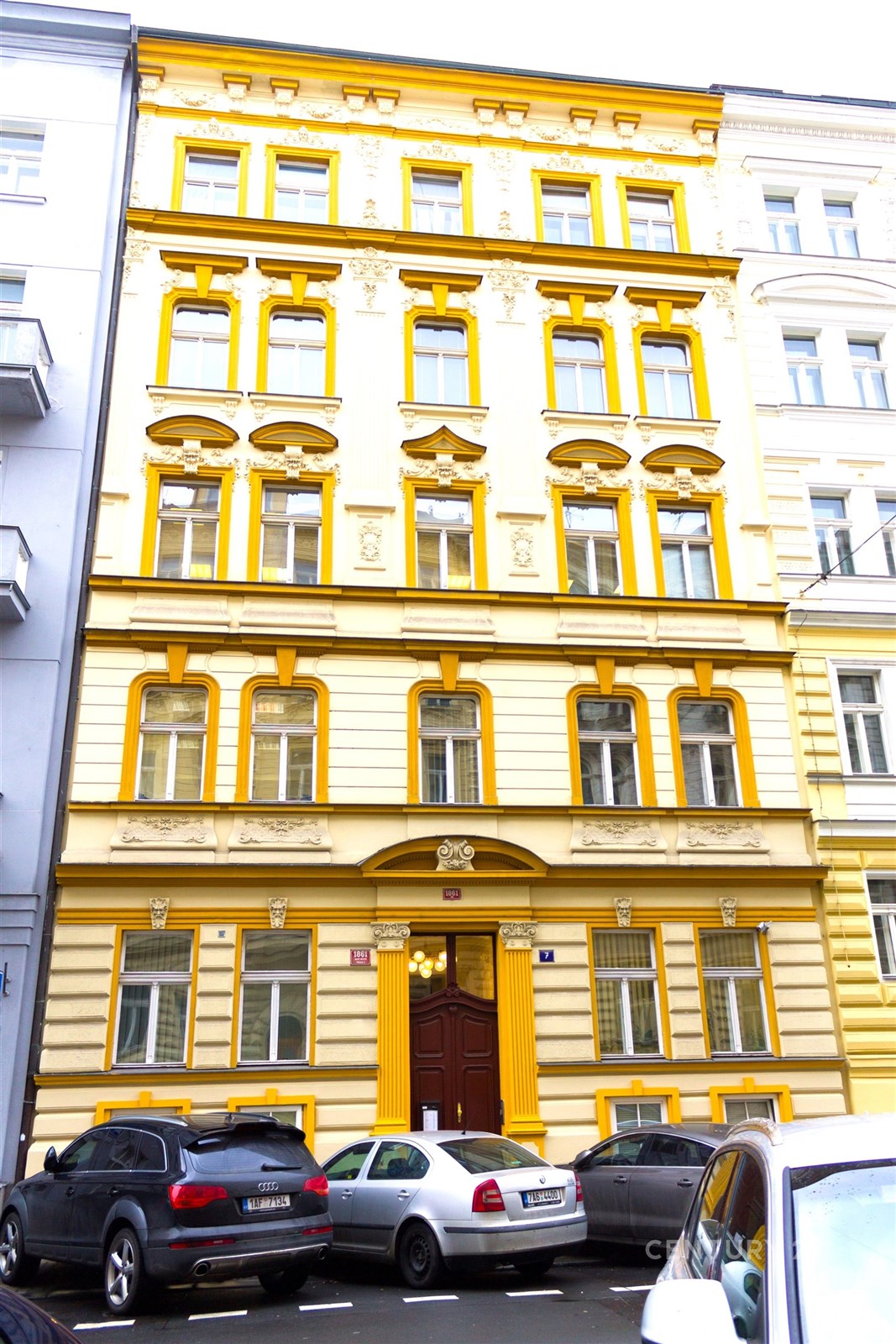 Historická fasáda s okny zdobenými štukovými detaily, renovovaný městský dům v centru. Skvělá lokalita a architektonický styl.