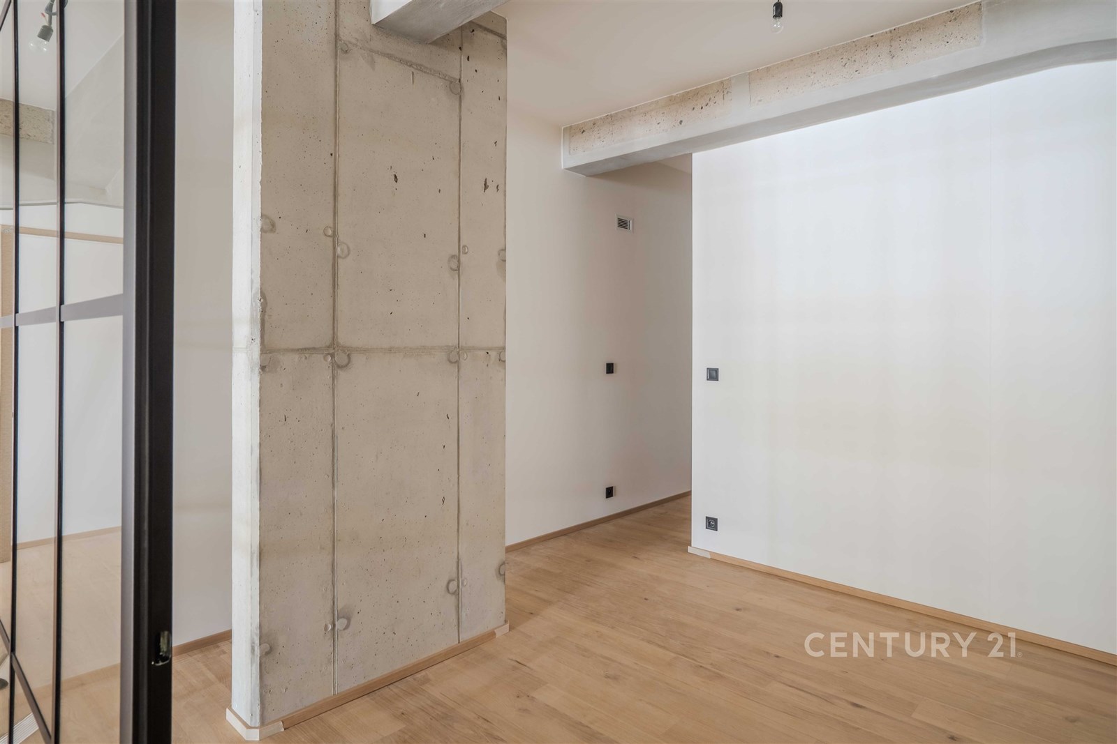 Moderní vstupní hala s parketovou podlahou, pohledovým betonem a minimalistickým designem v rekonstruovaném bytě