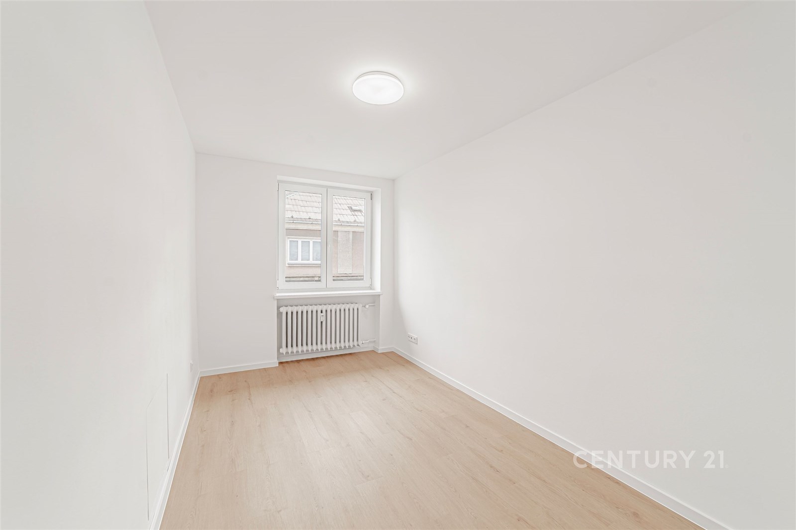 Světlý pokoj s parketovou podlahou, čistě bílé stě