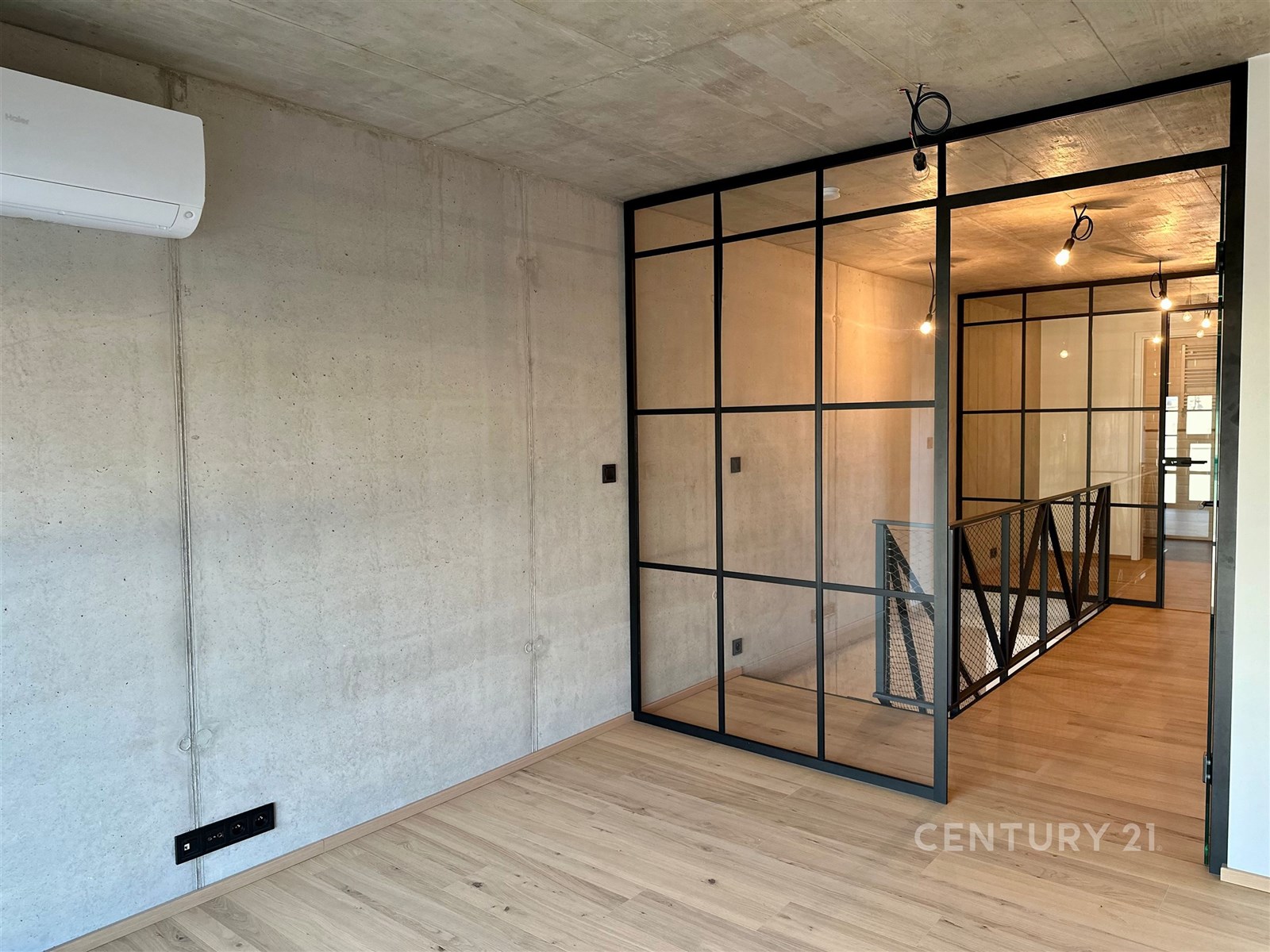 Průmyslový interiér s betonovými zdmi, parketovou podlahou a skleněnou příčkou, moderní klimatizace, prostorný světlý prostor