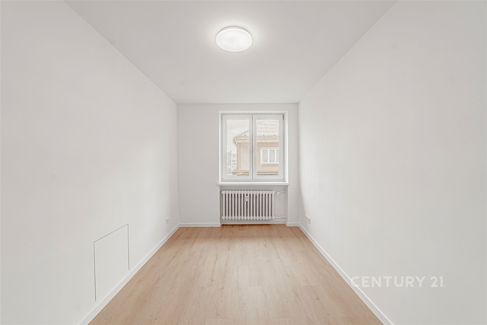 Světlý pokoj s parketovou podlahou, bílými stěnami