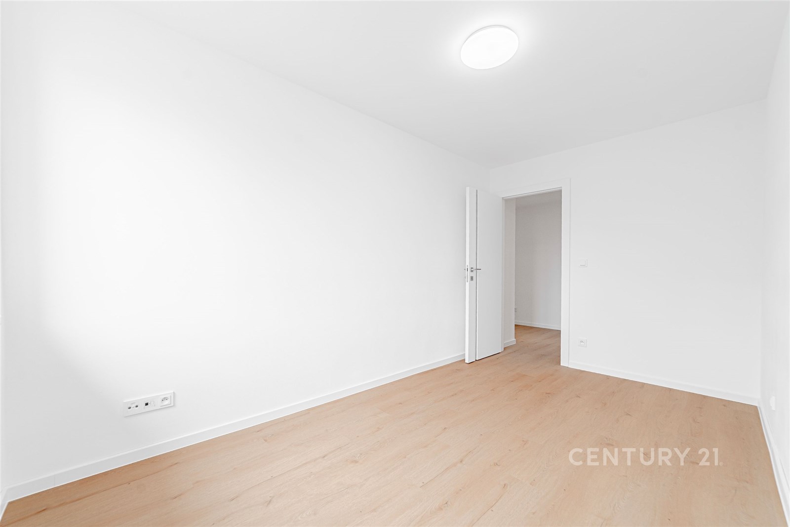 Prázdná místnost s dřevěnou podlahou, světlými stě