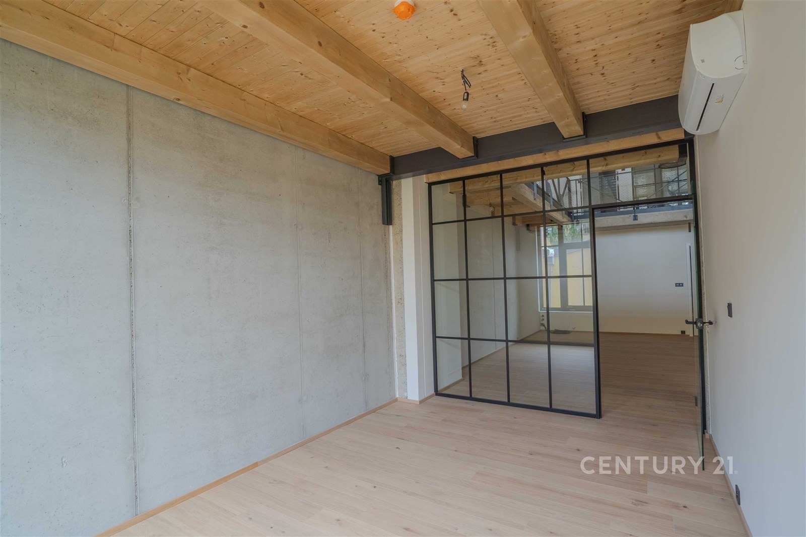 Průmyslový interiér s dřevěnými stropy, betonovými stěnami a skleněnými integrovanými dveřmi. Moderní design s kvalitními materiály.