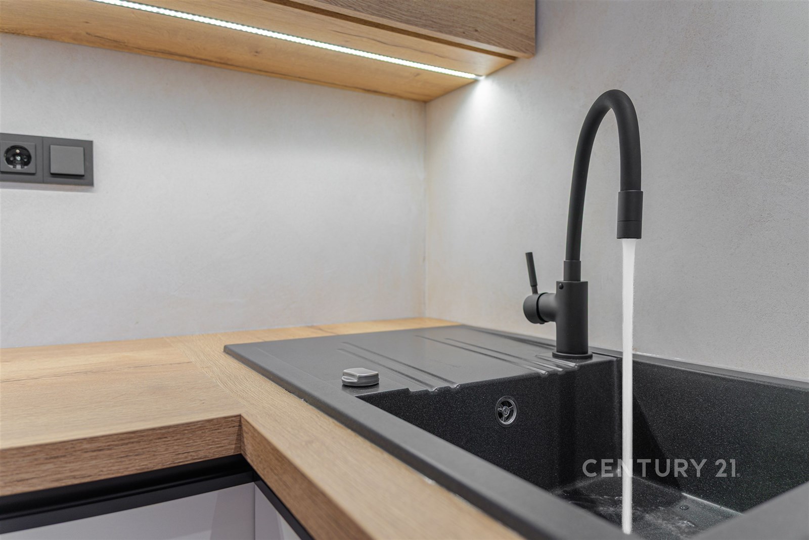 Moderní kuchyň s černým dřezem, matná baterie, dře