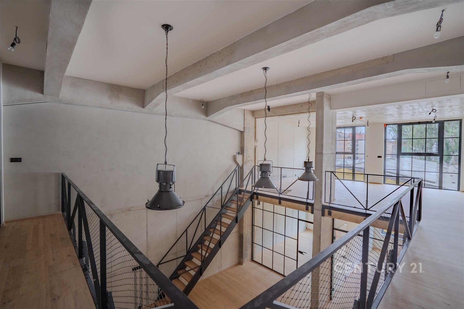 Útulné schodiště s dřevěnými schody, moderní kovové zábradlí a velká okna, kombinace industriálního a moderního stylu, světlý interiér.