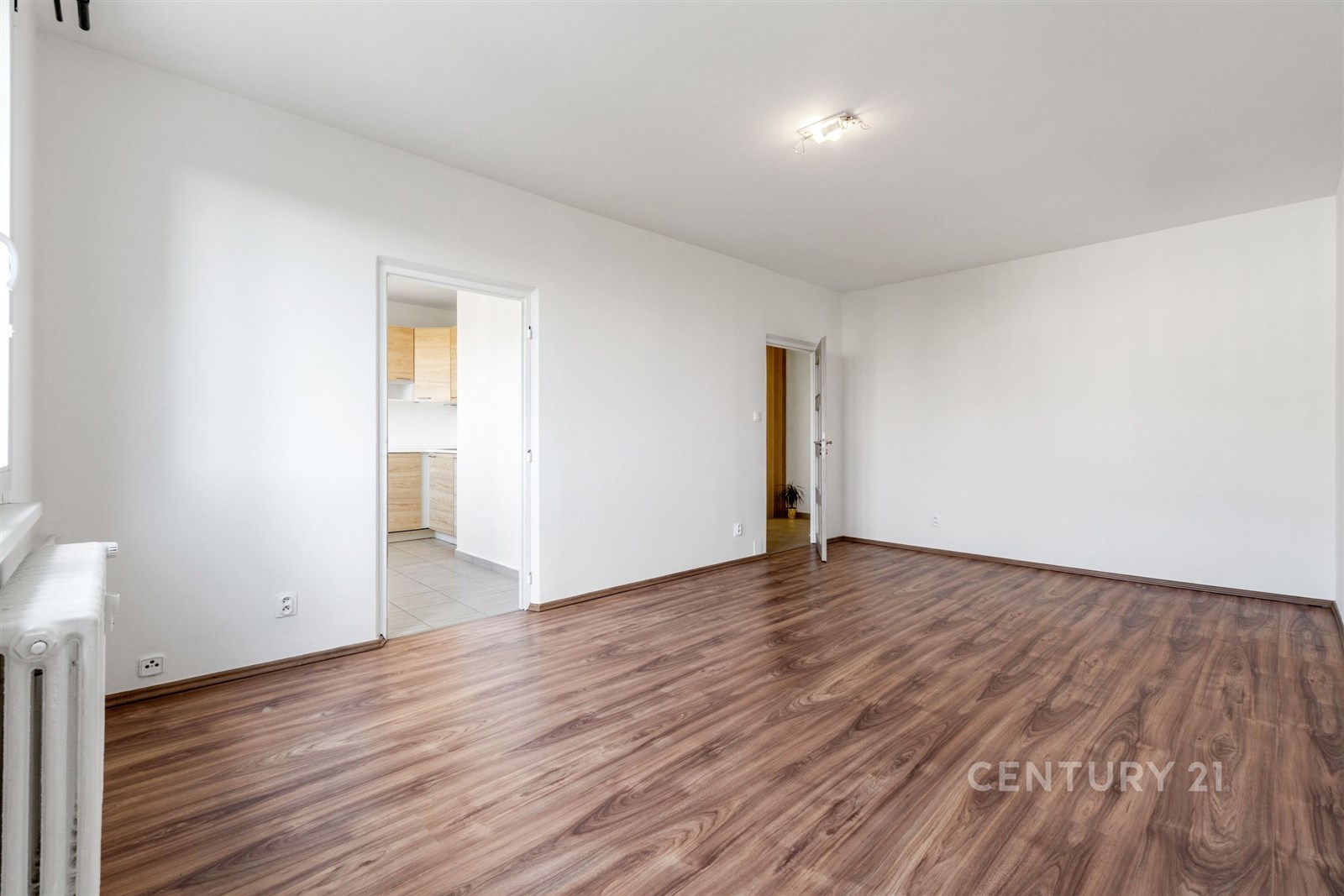 Prostorný obývací pokoj s parketovou podlahou, světlý interiér, moderní design, propojený s kuchyní.