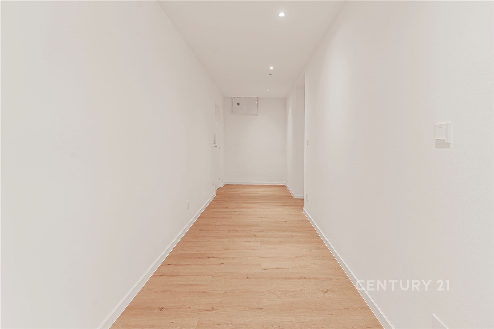 Úzká chodba s parketovou podlahou, bílými stěnami 