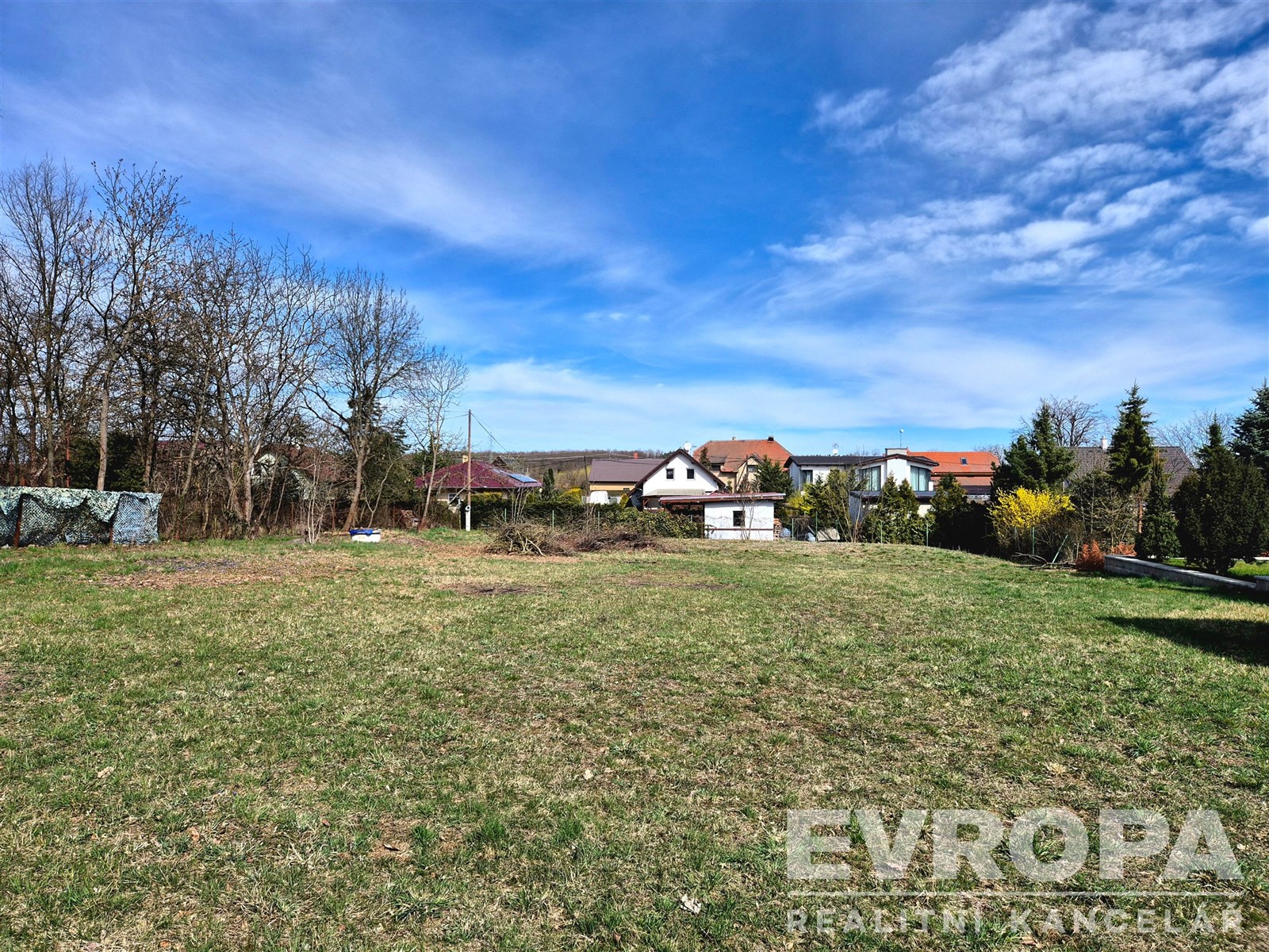 Zahrada s rovinatým terénem, obklopená zelení a st