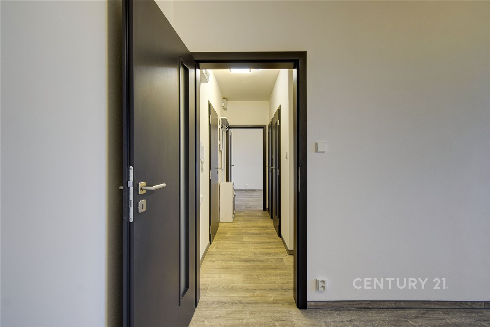 Úzká chodba s dřevěnou podlahou a moderními tmavým